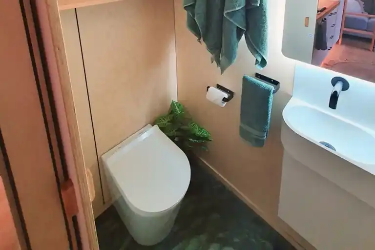 Compact bathroom with traditional flush toilet and backlit LED mirror.