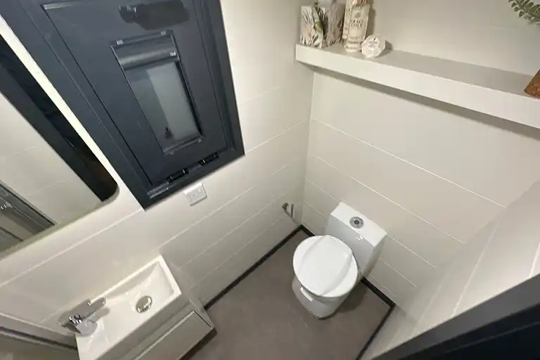 Modern bathroom with a glass shower panel and ceramic cassette toilet.