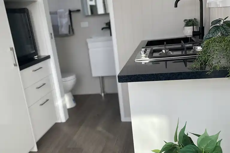 Kitchenette with timber benchtop, gas cooktop, and bar fridge space.